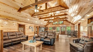 Un intérieur spacieux de chalet en bois, comprenant un salon, un coin repas et une cuisine.