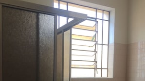 A bathroom with a toilet, a window with bars, and a door. - Pousada Cristal Limeira (Limeira)