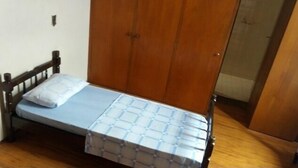 A small, single-bed room with a wooden headboard and a blue mattress. - Pousada Cristal Limeira (Limeira)
