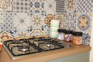 A kitchen with a gas stove and various spice jars on the counter.