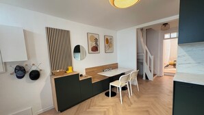 A modern kitchen with a herringbone wood floor, a wooden island, and a dining area with white chairs. - Pretty 50 m2 fisherman's cottage with exterior (Etaples)