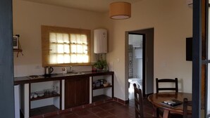 A compact kitchen with a built-in stove, a sink, and a window with blinds. - Posada del Santo Green & Rest (Cerrillos)
