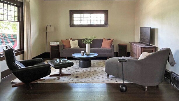 Ein Wohnzimmer mit Sofa, Sessel, Couchtisch und TV-Schrank.