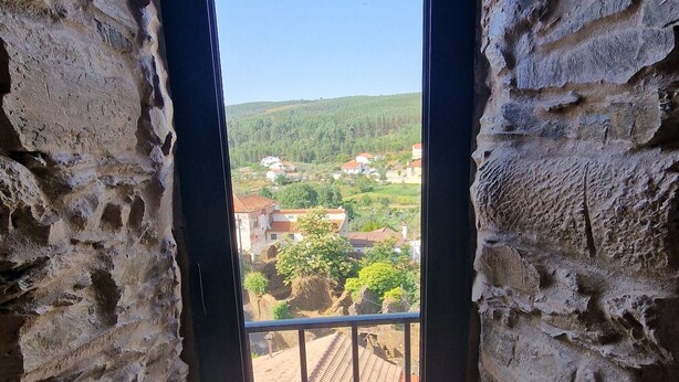 A room with a view of a village through a window with a metal railing. - Casinhas do Amioso T1 in the village of Amioso do Senhor in Alvares - Góis (Góis)