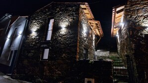 A stone building with a wooden staircase and a metal door. - Casinhas do Amioso T1 in the village of Amioso do Senhor in Alvares - Góis (Góis)