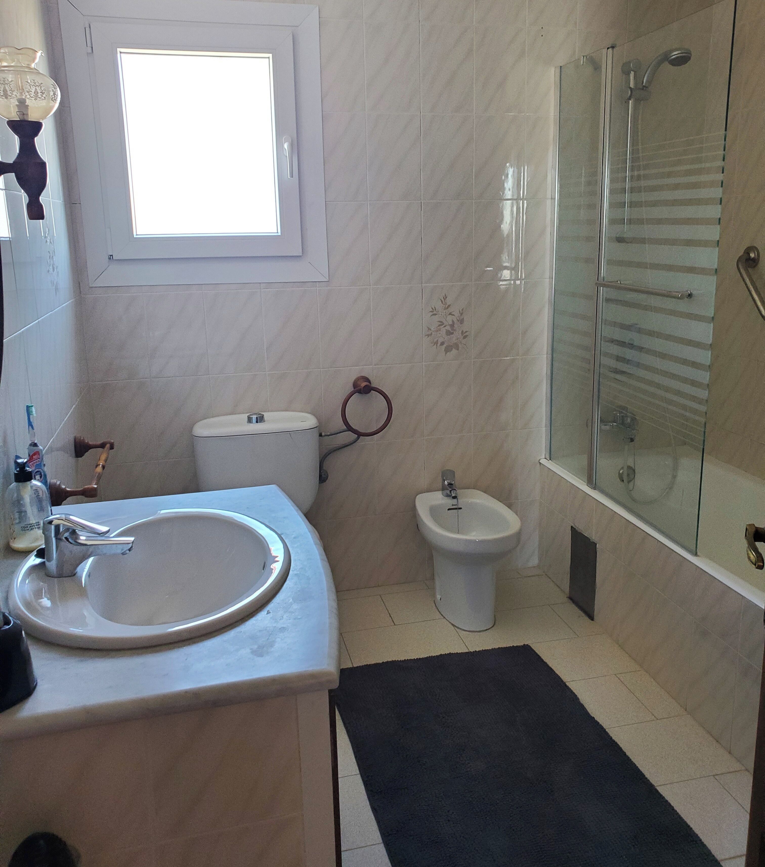 A bathroom with a sink, toilet, bidet, and glass-enclosed shower.