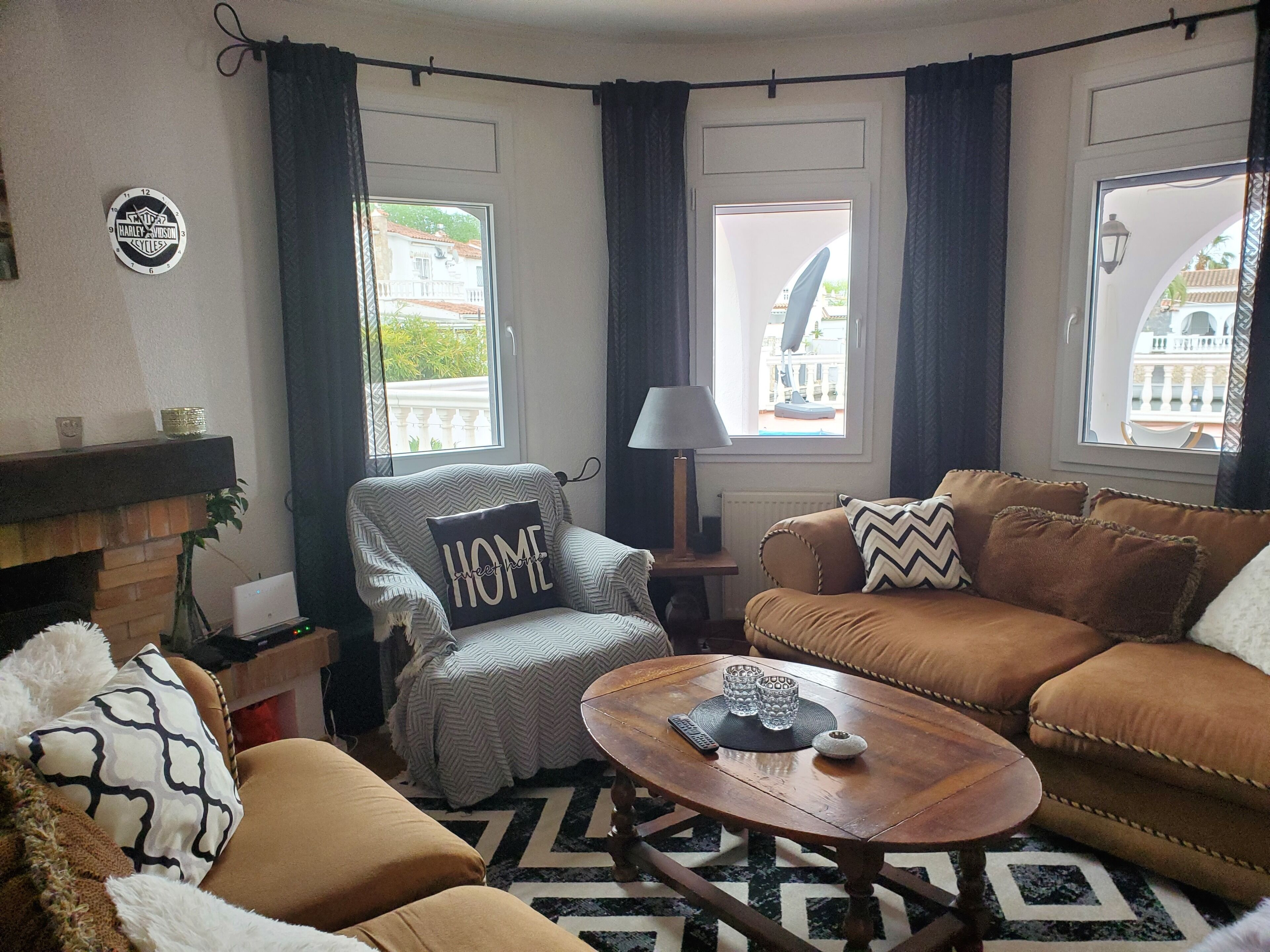 Un salón acogedor con sofá, sillón y mesa de centro, que cuenta con una chimenea, vistas a edificios y un reloj en la pared.