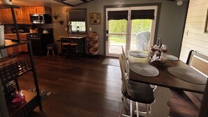 Una cocina con armarios de madera, una estufa y un fregadero. Hay una zona de comedor con una mesa y sillas.