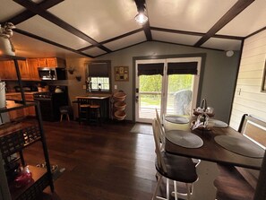 A kitchen with wooden cabinets, a stove, and a sink. There is a dining area with a table and chairs. - Feisty Ranch Farm Retreat - Private and charming 2-bedroom on 15 acres (Aquone)