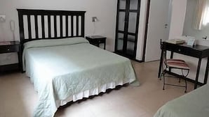 Une chambre à coucher avec un lit, un bureau, une chaise et une armoire.