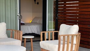 Un espace extérieur moderne aménagé avec des meubles en bois et une porte vitrée donnant accès à une chambre.
