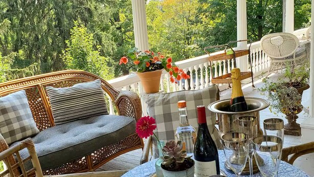 Un espacio al aire libre cubierto con mobiliario de mimbre, una mesa dispuesta para una comida y una botella de champán.