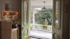 Una habitación con una puerta verde que da a un balcón con barandilla blanca y un farol colgante.