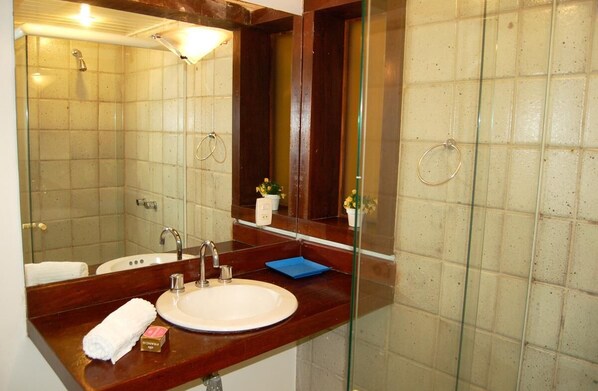 A bathroom with a large mirror, a sink, and a shower. - Pousada Bonfim (Búzios)