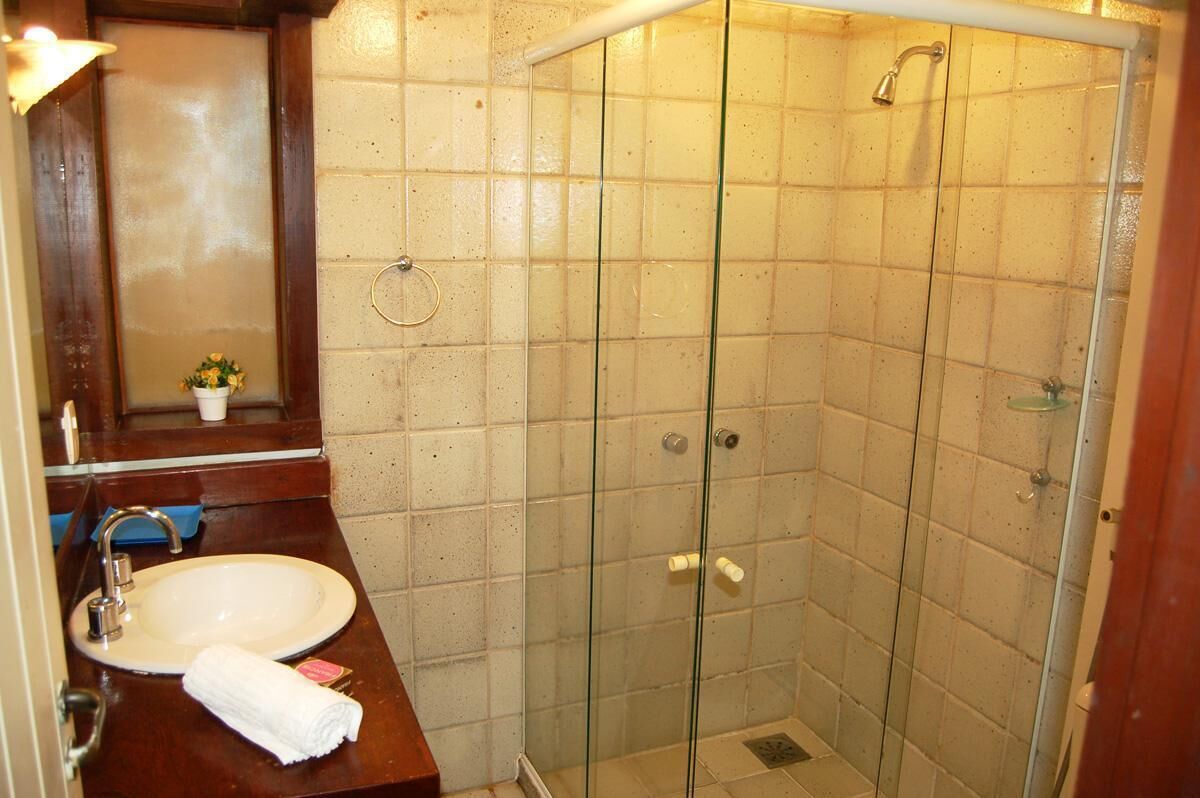 A bathroom with a glass-enclosed shower, a sink, and a mirror.