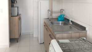Una cocina compacta con estufa a gas, un lavamanos y un microondas.