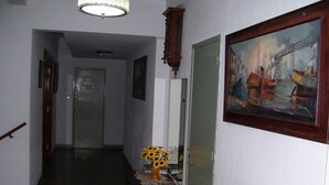 A hallway with a wooden bench, a vase of sunflowers, and a painting on the wall. - Hotel San Francisco (Santa Teresita)