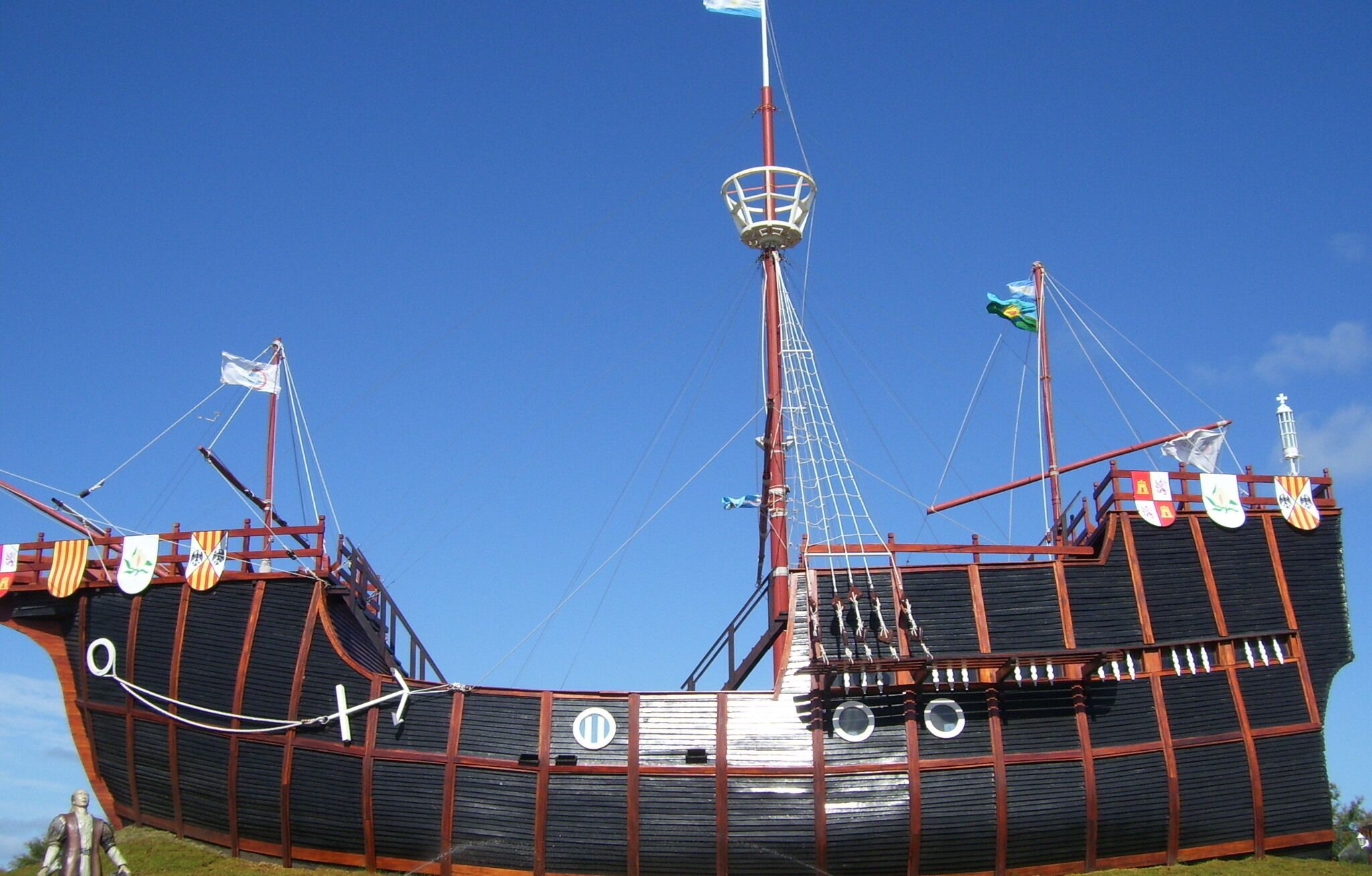 Suuri laiva, jossa on korkea masto, useita lippuja ja pelastusvene.