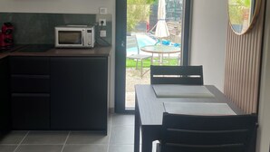 Une cuisine compacte équipée d’un four à micro-ondes, de placards et d’un coin repas avec une table et des chaises.