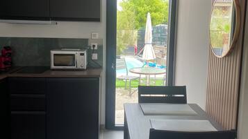 Une cuisine compacte équipée d’un four à micro-ondes, de placards et d’un coin repas avec une table et des chaises.