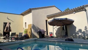 Un espace aménagé au bord de la piscine, comprenant une chaise longue, une table et un parasol.