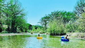 A clear river with two people in inflatable tubes.