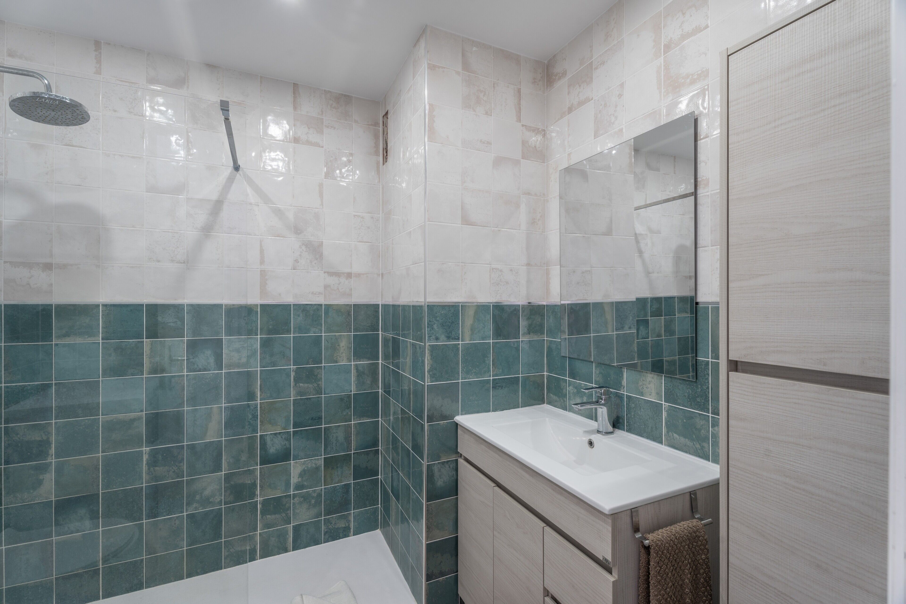 Een moderne badkamer met een douche, een wastafel en een spiegel.