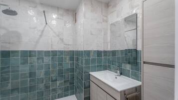 Een moderne badkamer met een douche, een wastafel en een spiegel.