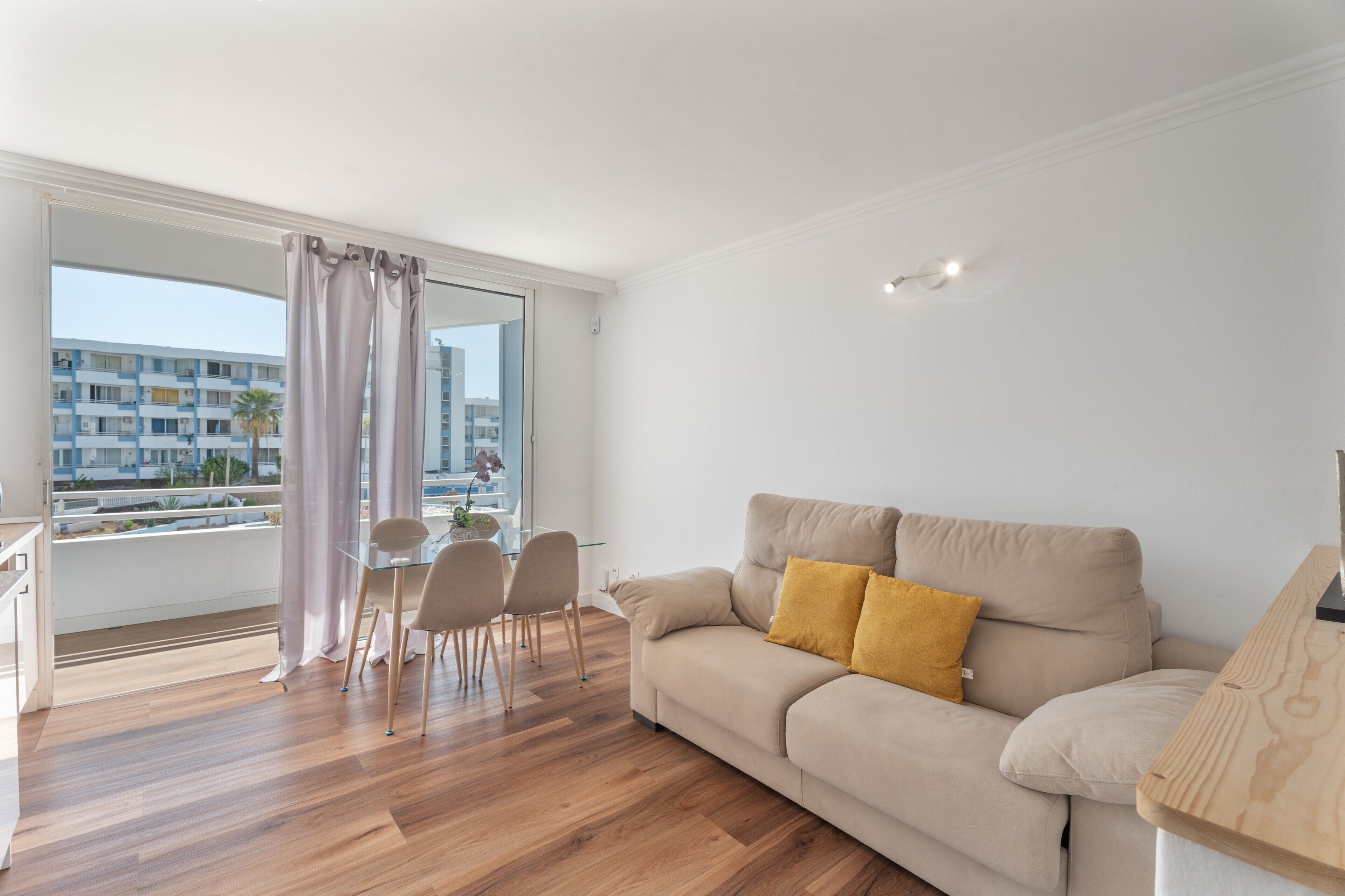 Een moderne woonkamer met een bank, een glazen eettafel en stoelen.