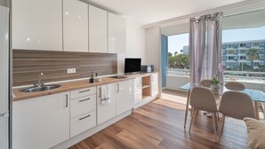 A modern kitchen with a built-in microwave, a sink, and a dining area with a glass table and chairs. - Vacation Studio 'Golf Del Sur' with Shared Pool, Balcony and Wi-Fi (San Miguel de Abona)