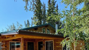 A log cabin with a porch, a table, and chairs. - Burnt Paw House-Modern Comfort in the Last Frontier (For families or casual travelers) (Tok)