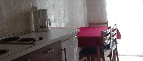 A kitchen with a coffee maker, a sink, and a dining area with a table and chairs.