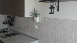 Una cocina moderna con un lavamanos empotrado, una planta colgante y un farol en la pared.