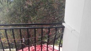 A balcony with a white chair, a red cloth, and a blue cover.