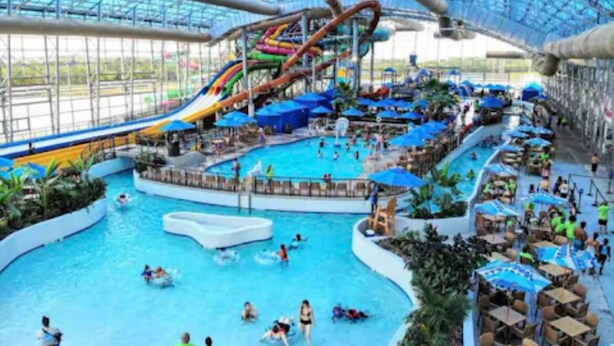 Parque acuático interior con múltiples piscinas, toboganes y zonas de descanso.