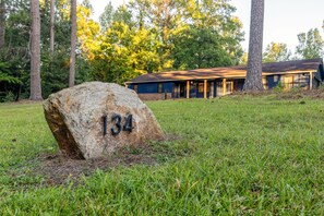 A large rock with the number 134 in a grassy area with a building in the background. - 4 Bedroom Retreat w/ Hot Tub on Private Acre of Wooded Land (Fountain Inn)
