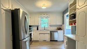 A kitchen with white cabinets, a stainless steel refrigerator, a microwave, and a dishwasher.