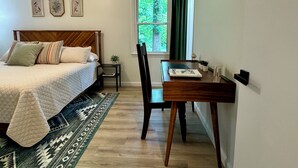 A bedroom with a bed, a desk, a chair, a window with curtains, and a rug.
