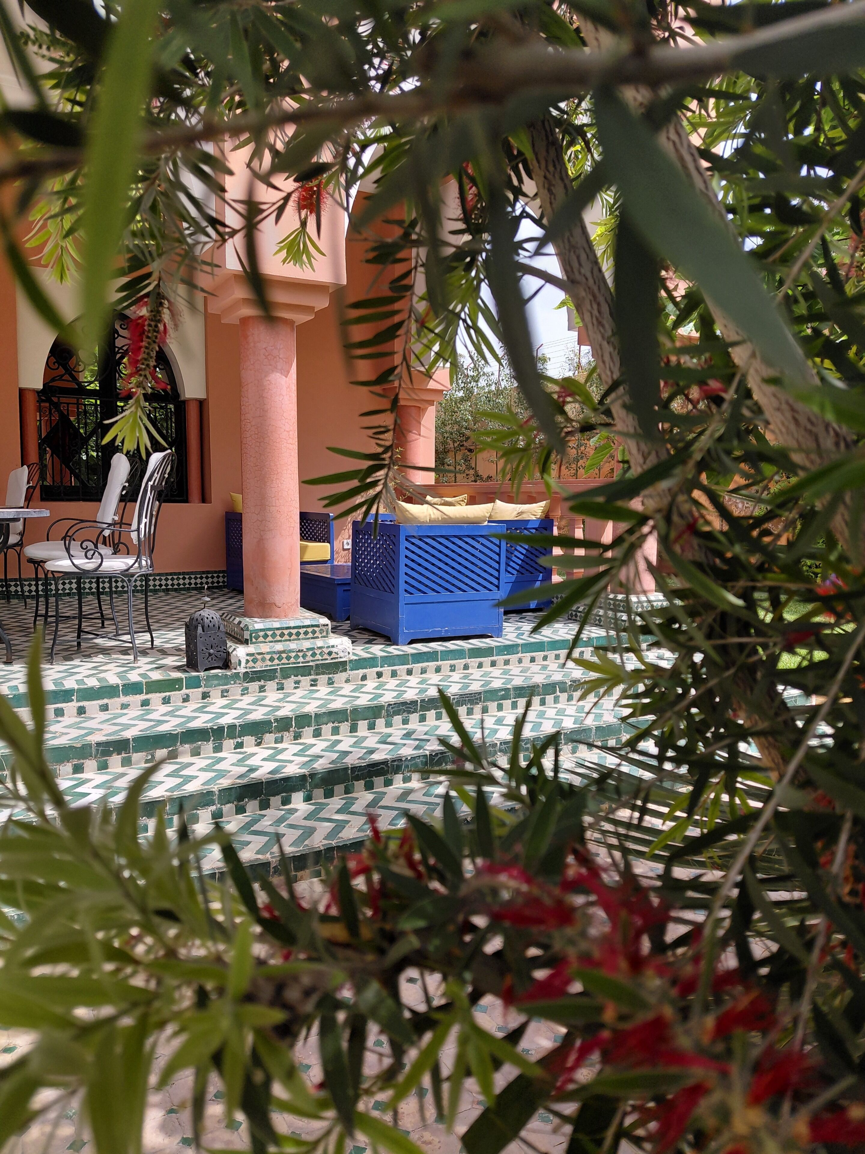A courtyard with a tiled floor, a blue seating area, and a chair.