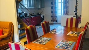 Un coin repas avec une table en bois, des chaises à rayures et une cuisine en arrière-plan.