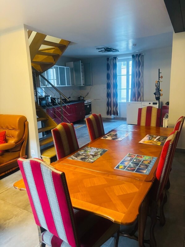 Un comedor con una mesa de madera, sillas a rayas y una cocina al fondo.