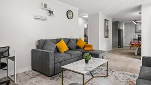 A modern living room with a grey sofa, a small coffee table, and a colorful rug.