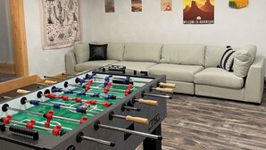 A room with a foosball table, a sofa, and a wall with various posters.