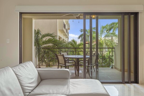 Un balcon avec une porte vitrée, un canapé blanc et une table avec des chaises.