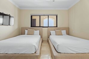 Une chambre d’hôtel avec deux lits, une fenêtre donnant sur un beau paysage et un ventilateur de plafond.