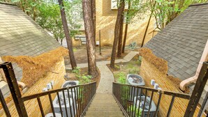Una escalera que lleva a un jardín en la azotea, con árboles y mobiliario exterior.