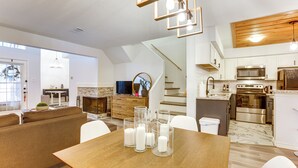Una cocina moderna con electrodomésticos de acero inoxidable, un comedor con mesa de madera y una sala de estar con sofá y televisor.