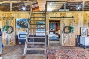 A rustic interior with wooden walls, a loft area, a bed, and a ladder leading to a loft. - BBQ Ready: Farm-Style Kinston Hideaway w/ Pool (Kinston)