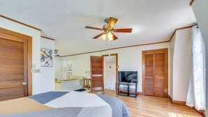 A bedroom with a large bed, wooden doors, a ceiling fan, a TV, and a bathroom visible through an open door. - 2 Mi to Dtwn Pittsburgh: Family-Friendly Townhome! (Pittsburgh)