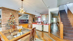 A spacious kitchen with a brick wall, wooden dining table, and a staircase leading to an upper level. - 2 Mi to Dtwn Pittsburgh: Family-Friendly Townhome! (Pittsburgh)